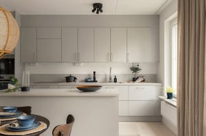 Modernt vitt kök med köksö, ljusa skåpsluckor och dukat matbord vid fönster