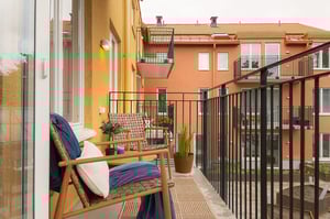 Inglasad balkong med sittgrupp och utsikt mot flerfamiljshus