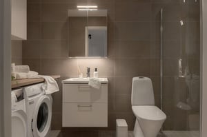 Modernt badrum med tvättmaskin, handfat, toalett och dusch