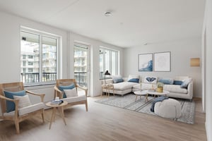 Inflyttningsklart vardagsrum med ljusa väggar, soffa, fåtöljer och stora fönster