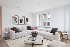 Ljust och stilrent vardagsrum med ljus L-formad soffa, abstrakt väggkonst, marmorbord och stora fönster