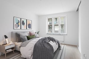 Inflyttningsklar lägenhet med sovrum, dubbelsäng, nattduksbord och stora fönster
