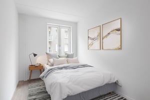 Inflyttningsklar lägenhet med bäddad säng, sängbord och ljusa väggar