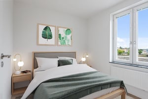 Sovrum med dubbelsäng, gröna detaljer och fönster med utsikt