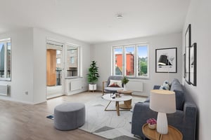 Inflyttningsklar lägenhet med ljus vardagsrumsmiljö, grå soffa, fåtölj och stora fönster