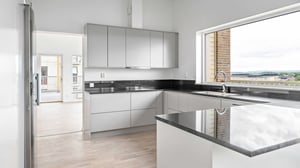 Inflyttningsklar lägenhet med modernt kök, ljusa skåpsluckor, svart bänkskiva och stort fönster