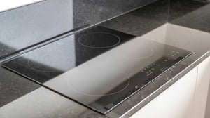 Inflyttningsklart kök med svart induktionshäll och bänkskiva i sten