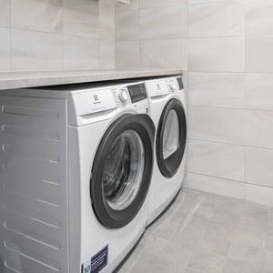 Badrum med frontmatad tvättmaskiner och torktumlare under en bänkskiva