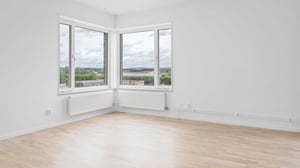 Inflyttningsklart vardagsrum med stora fönster och ljusa väggar