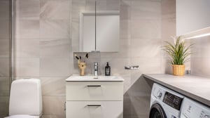 Inflyttningsklart badrum med tvättmaskin, handfat och duschhörna