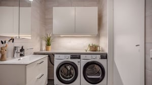Inflyttningsklart tvättrum med tvättmaskin, torktumlare, handfat och vita skåp