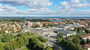 Flygvy över stad med bostadsområde, vägar, grönområden och hav i bakgrunden