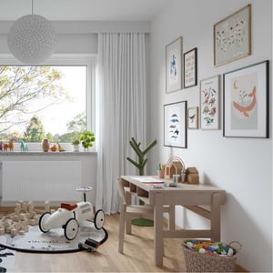 Ljust barnrum med skrivbord, leksaker och fönster mot trädgård