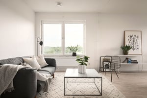 Inflyttningsklart vardagsrum med soffa, soffbord, fönster och ljusa väggar