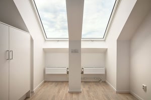 Inflyttningsklart rum med takfönster, ljusa väggar och trägolv