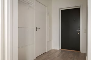 Inflyttningsklar lägenhet med vit hall, garderobsdörrar och svart ytterdörr