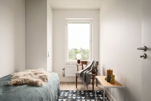 Inflyttningsklar lägenhet med ljust sovrum, säng, stol och fönster