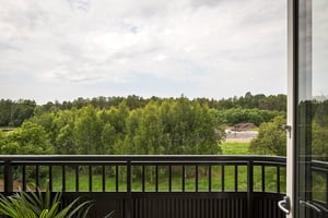 Utsikt från balkong mot grönskande träd och himmel