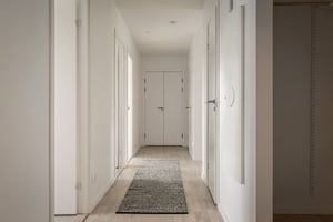 Inflyttningsklar lägenhet med ljus hall, vita väggar och en lång matta på golvet
