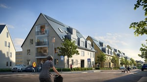 Bostadskvarter med moderna flerbostadshus, balkonger och gröna träd längs gatan. Cyklist i förgrunden och människor som rör sig på trottoaren