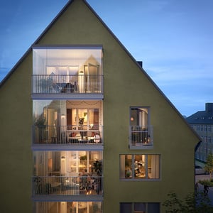 Fasad på bostadshus med flera upplysta balkonger och lägenheter i kvällsljus