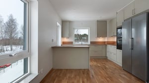 Inflyttningsklar lägenhet med modernt kök, vita skåpsluckor, träbänkskiva och rostfri kyl och frys