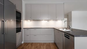 Inflyttningsklar lägenhet med modernt grått kök, rostfria vitvaror och trägolv