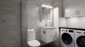 Badrum med grå kakelväggar, kommod med handfat, spegelskåp, duschvägg och tvättmaskin samt torktumlare