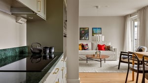 Lägenhet med kök och vardagsrum i öppen planlösning, ljus inredning och soffgrupp