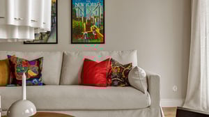 Vardagsrum med ljus soffa, färgglada prydnadskuddar och väggkonst