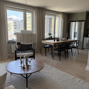 Inflyttningsklar lägenhet med ljus vardagsrumsdel, matplats, stora fönster och moderna möbler
