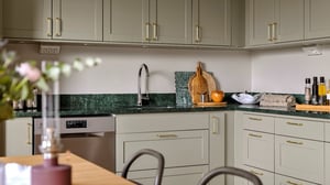 Kök med ljusa skåp, gröna bänkskivor och rostfri diskho