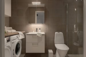 Modernt badrum med tvättmaskin, handfat, toalett och dusch