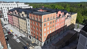 Flerbostadshus med färgglada fasader i en nybyggd stadsdel, omgiven av grönska och moderna byggnader