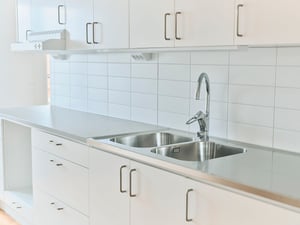 Inflyttningsklart kök med vita skåpluckor, dubbel diskho och kaklad vägg