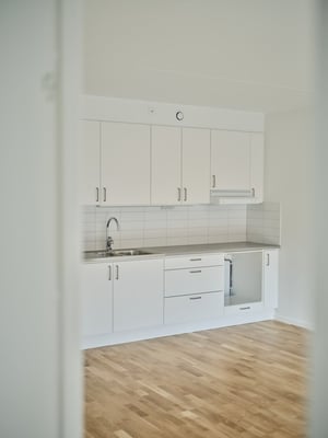 Inflyttningsklart kök med vita skåp, diskho och ljus trägolv