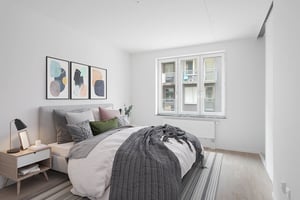 Inflyttningsklar lägenhet med sovrum, dubbelsäng, nattduksbord och stora fönster