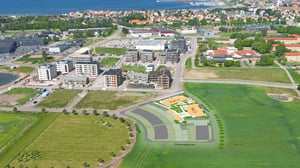 Flygvy över ett bostadsområde med nybyggda flerbostadshus, vägar och gröna fält. Planillustration för kommande bostadsområde vid Planetgatan