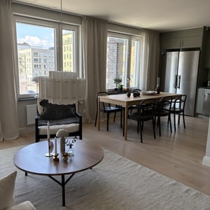 Inflyttningsklar lägenhet med ljus vardagsrumsdel, matplats, stora fönster och moderna möbler