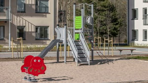 Lekplats med rutschkana, klätterställning och gungdjur i ett bostadsområde