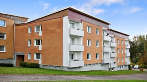 Flerbostadshus i tegel med vita balkonger och grön gård