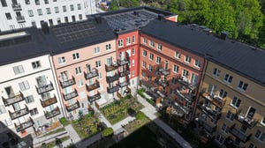 Flerfamiljshus med färgglada fasader, balkonger och en grön innergård med trädgårdsytor
