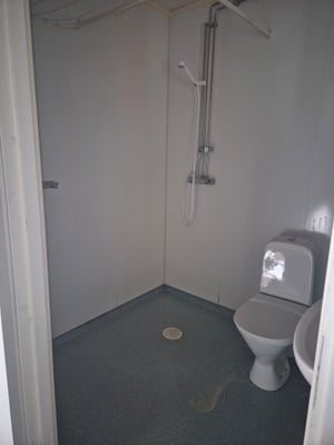 Ett litet, enkelt badrum med duschmunstycke, toalett och handfat