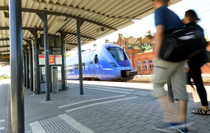 Två personer går på en tågperrong vid ett blått tåg