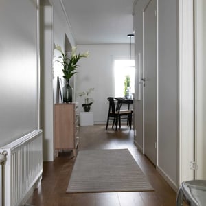Lägenhet med hall, trägolv, ljusa väggar och matplats i bakgrunden