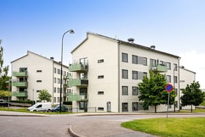 Flerbostadshus i ljus puts med gröna balkonger