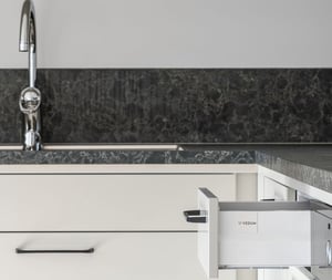 Kök med vit diskho, kromad blandare och utdragen låda i modern lägenhet