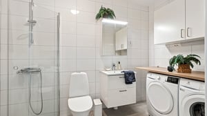 Inflyttningsklart badrum med dusch, handfat, toalett och kombinerad tvättmaskin och torktumlare