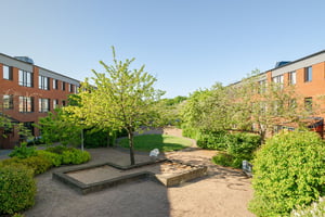 Innergård med sandlåda och gröna buskar