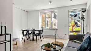 Inflyttningsklar lägenhet med ljus öppen planlösning, matplats, vardagsrum och utgång mot grön innergård
